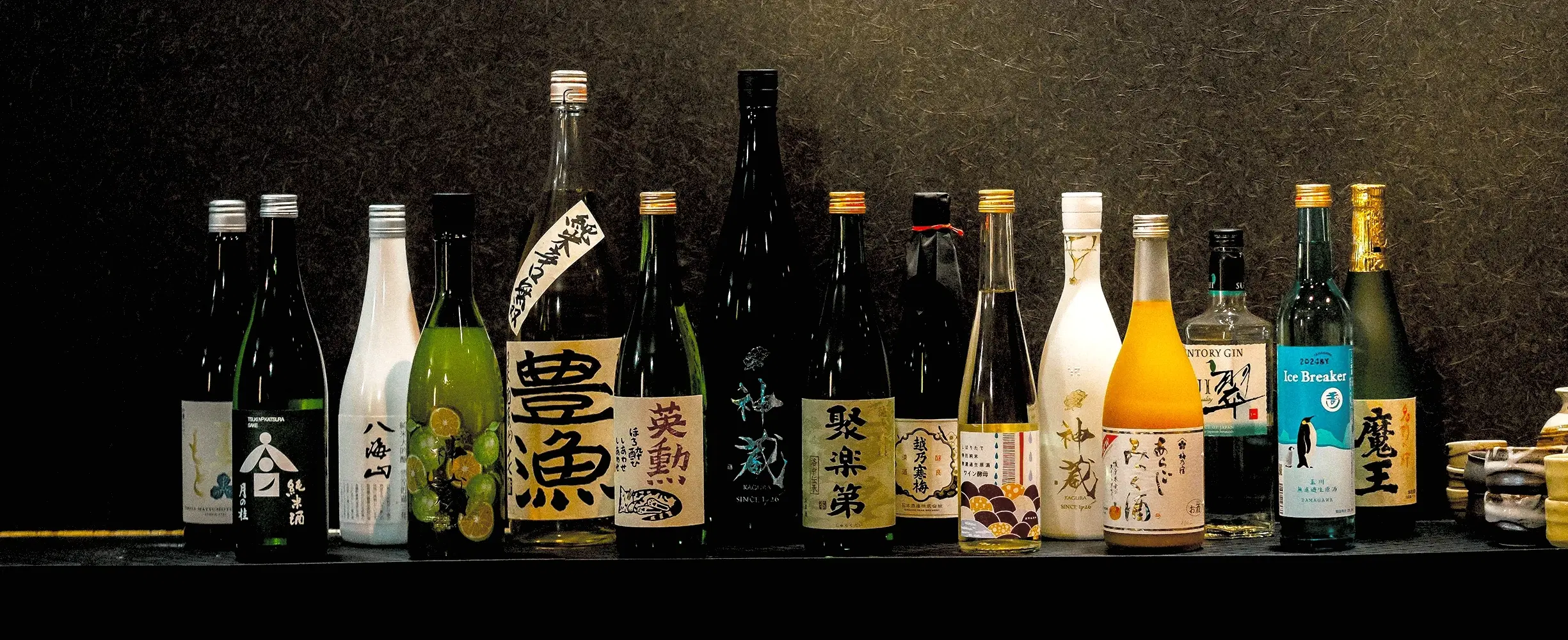 カウンター奥に並んだ日本酒の瓶